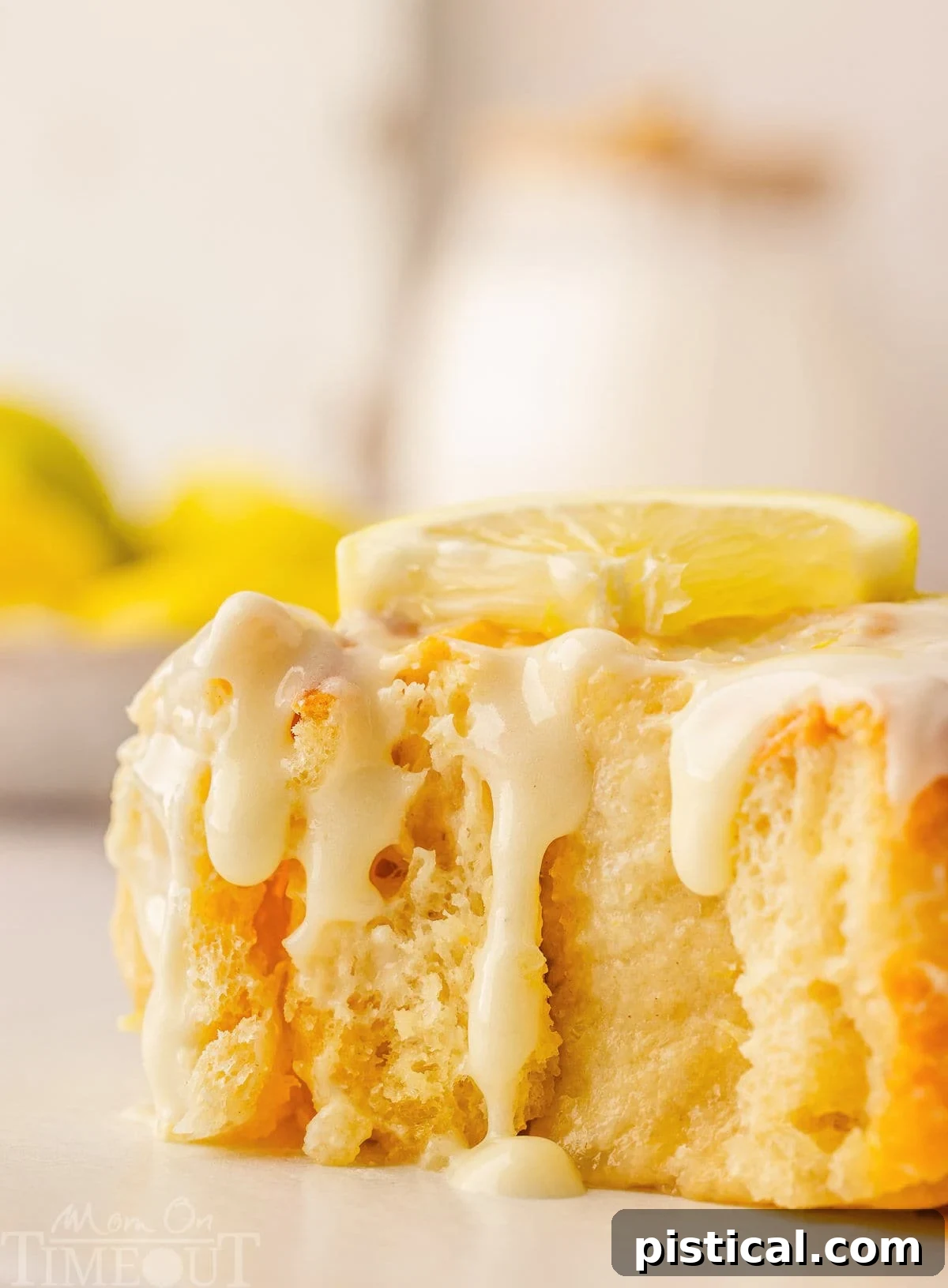 Zesty Lemon Swirls 7 A side view of a perfectly baked lemon roll, showing the glaze dripping down and a gentle bite taken out of it.