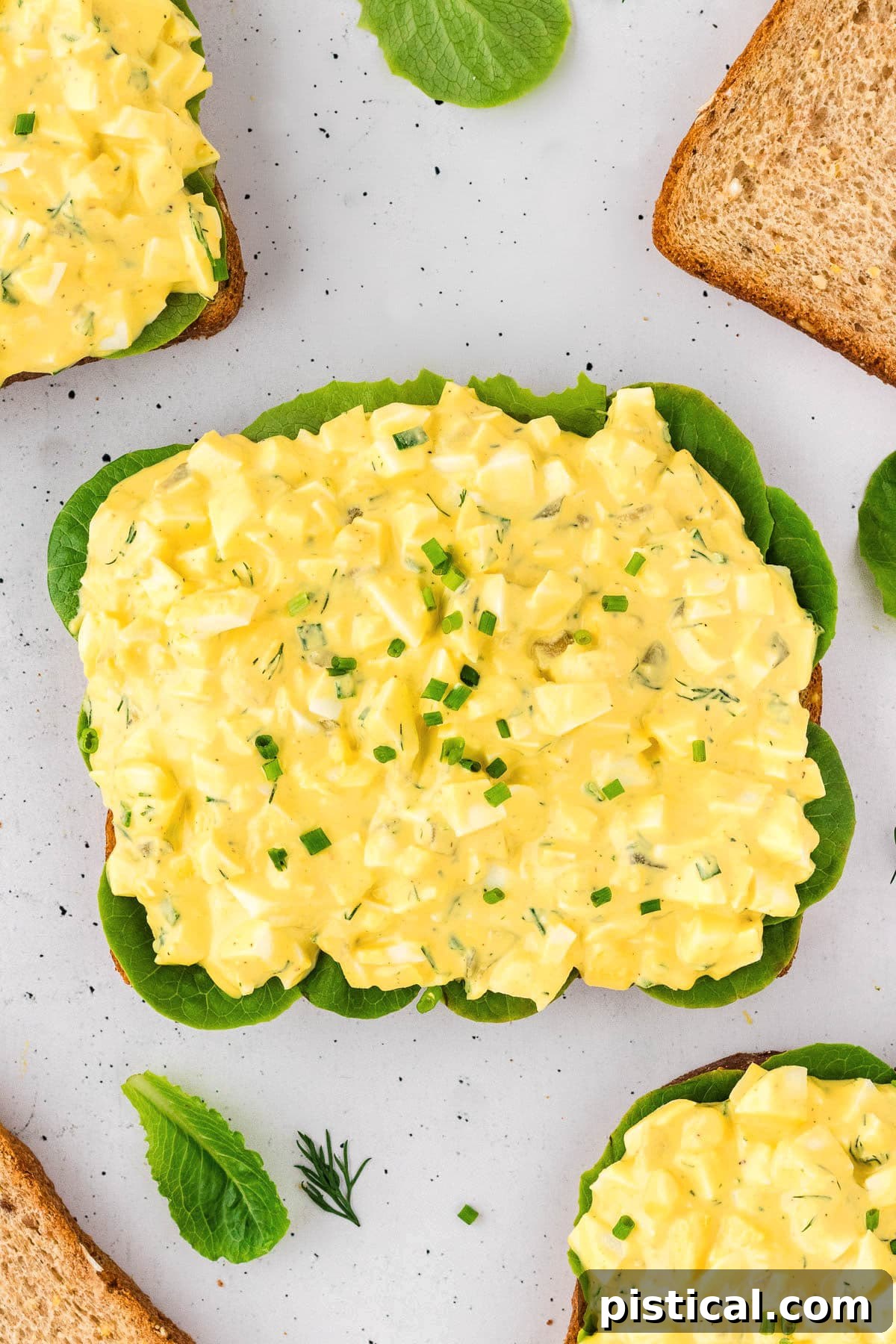 A top down view of egg salad on a piece of bread.