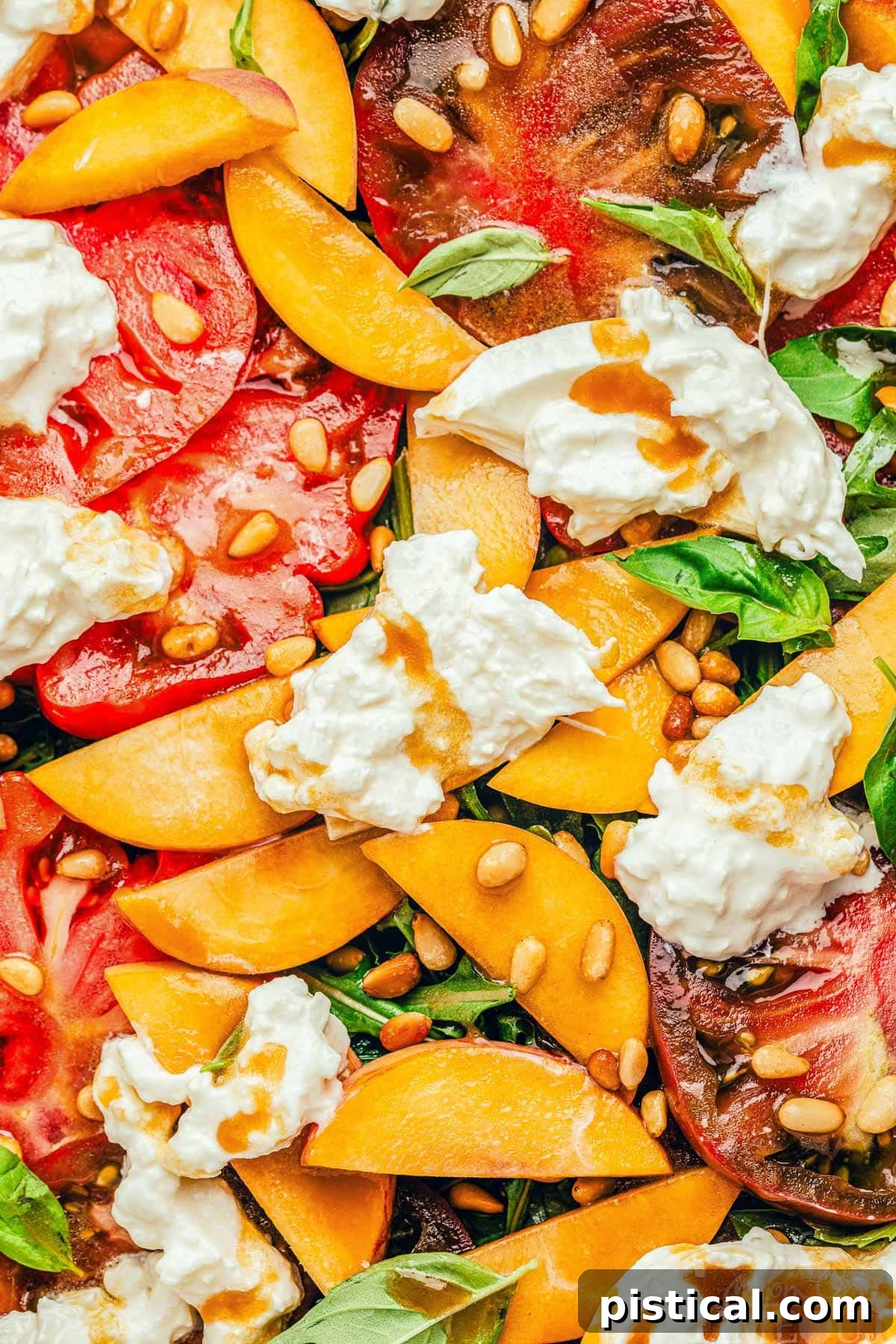A close-up view of the Peach Burrata Salad beautifully arranged on a white platter, highlighting slices of ripe peaches and heirloom tomatoes nestled among arugula, topped with creamy burrata cheese and a generous drizzle of balsamic dressing.