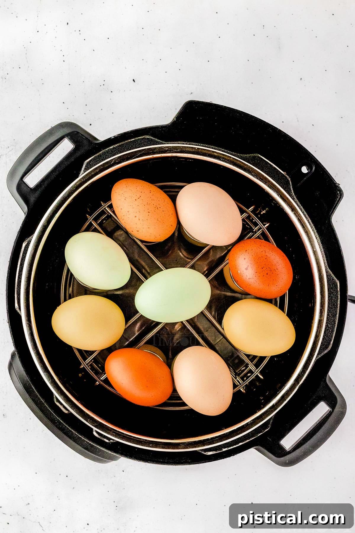 Top down view of perfectly hard-boiled eggs resting on a metal trivet inside an Instant Pot, ready to be removed.