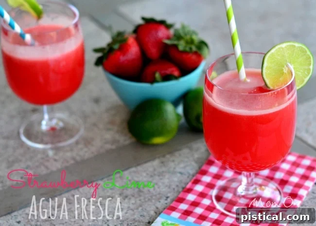 Close-up of freshly prepared strawberry lime agua fresca with whole strawberries and lime wedges, emphasizing natural ingredients.