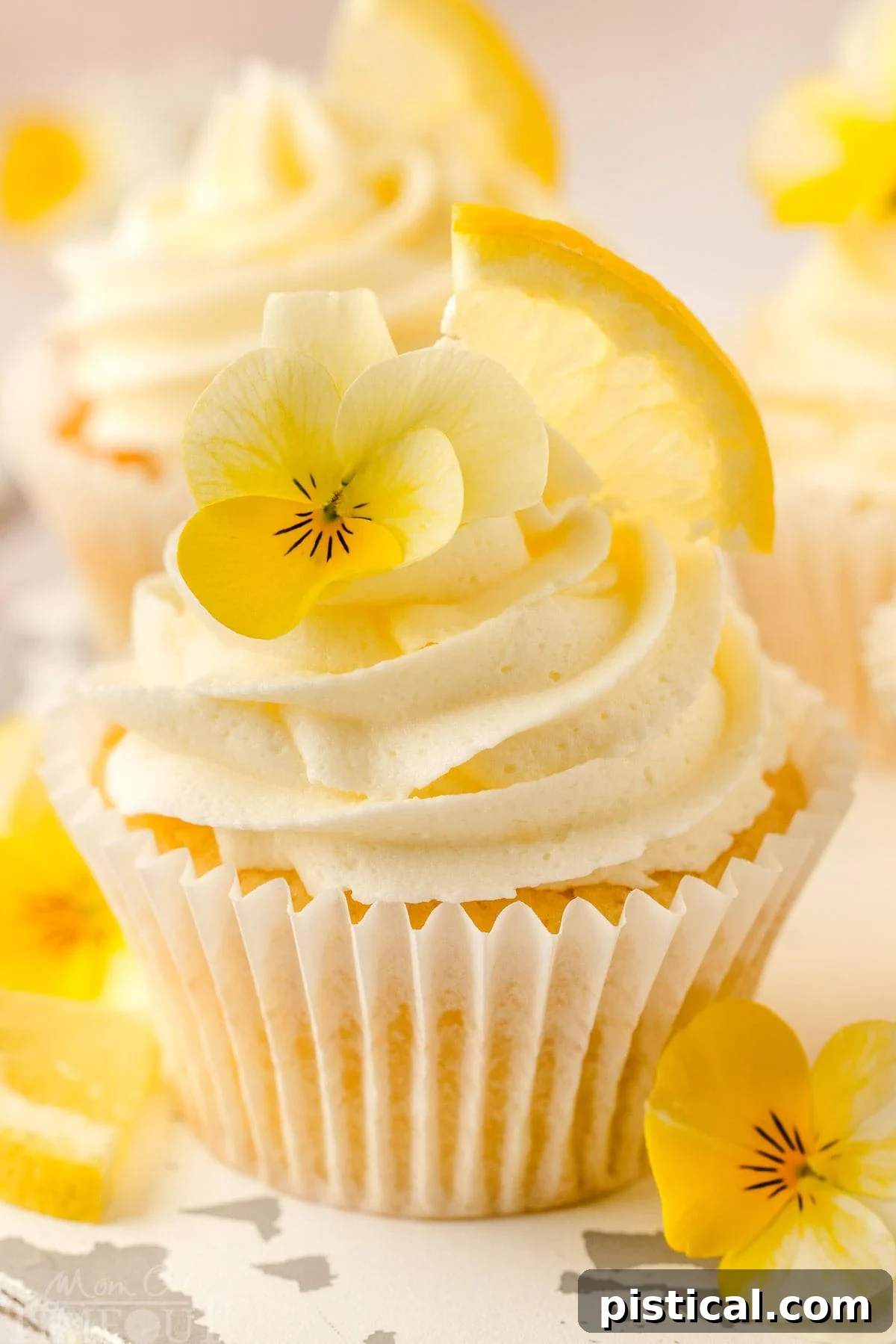 Zesty Lemon Delight Cupcakes 3 A lemon cupcake with a lemon wedge and flower garnishing it.