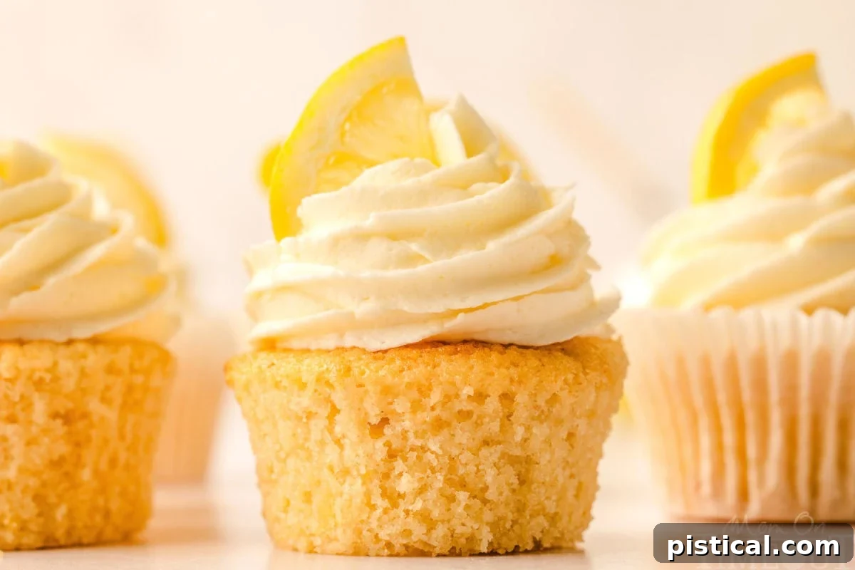 Zesty Lemon Delight Cupcakes 5 Side view of three lemon cupcakes.