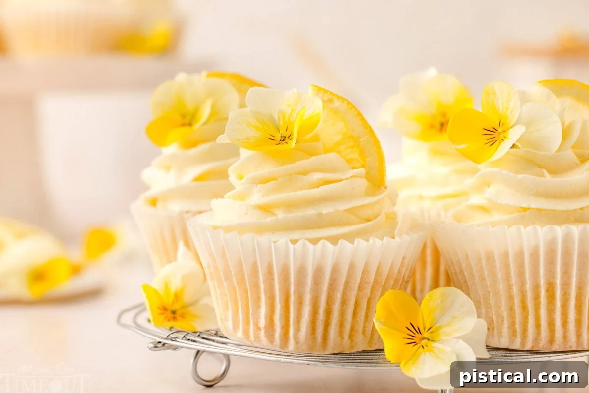 Zesty Lemon Delight Cupcakes 8 Lemon cupcakes on metal rack frosted beautifully with lemon buttercream and garnished with a small yellow pansies.