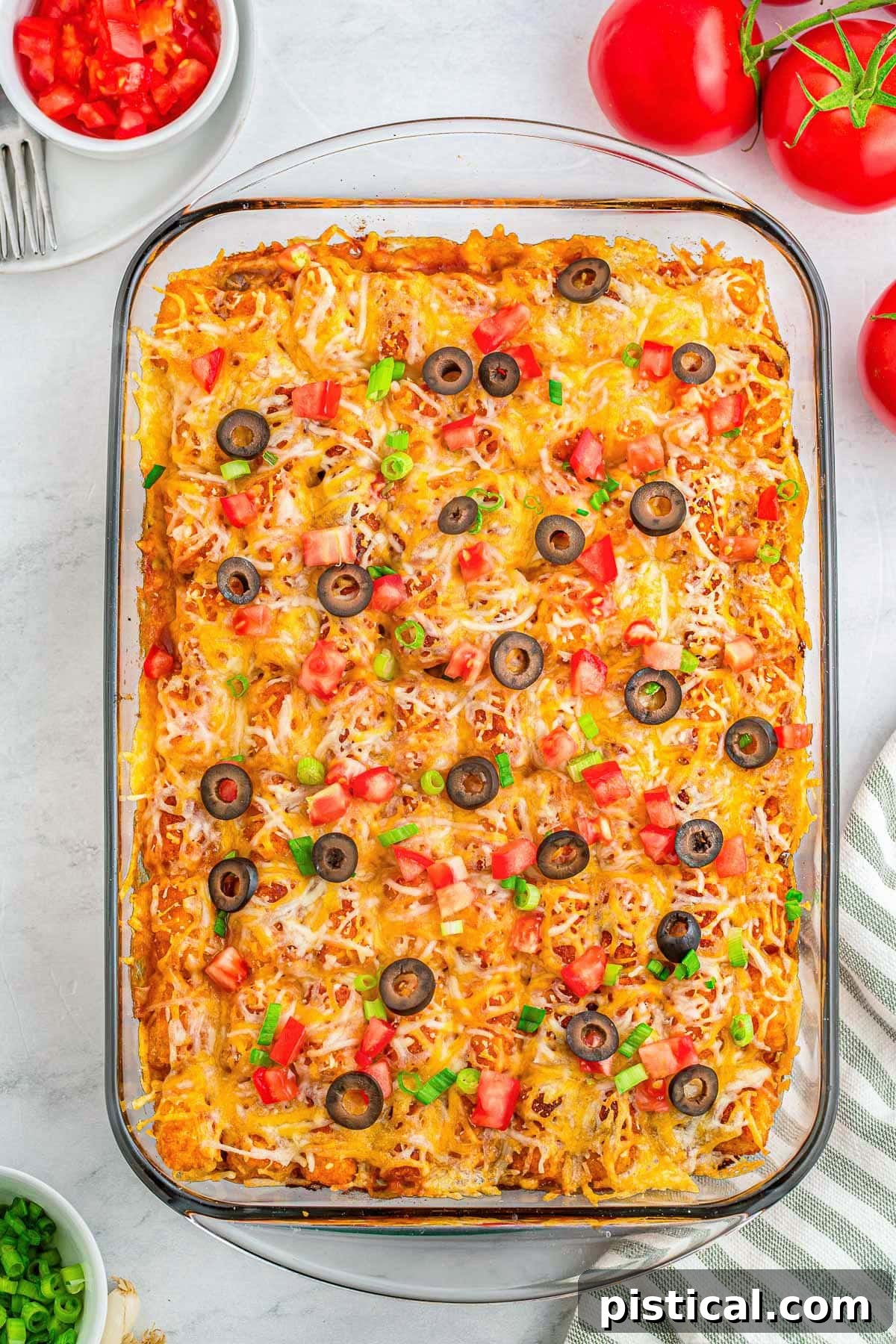 A mesmerizing top-down perspective of a bubbling Mexican Tater Tot Casserole, freshly baked in a clear glass baking dish, showcasing its golden-brown tater tot crust and cheesy filling.