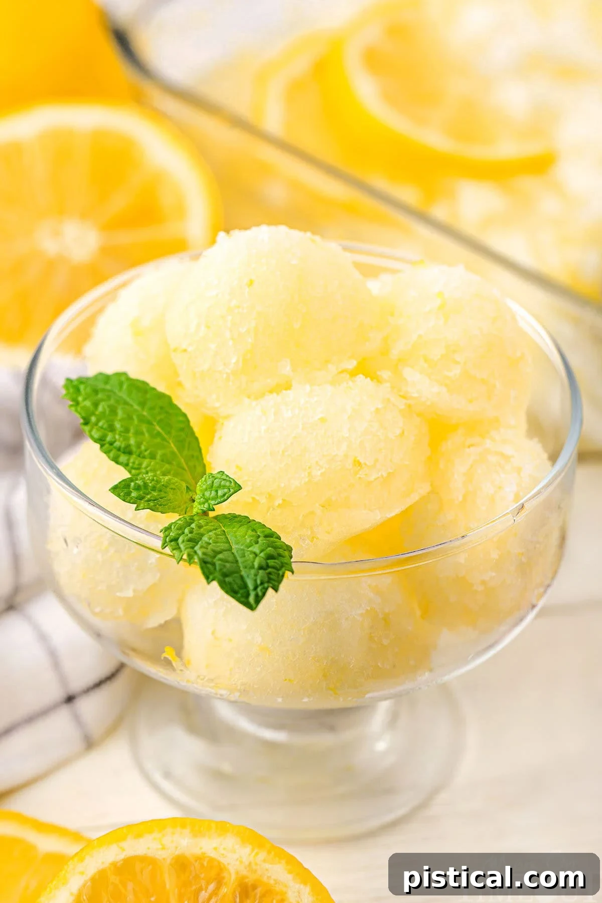 A refreshing glass of homemade lemon sorbet, garnished with a vibrant green mint leaf, ready to be enjoyed.