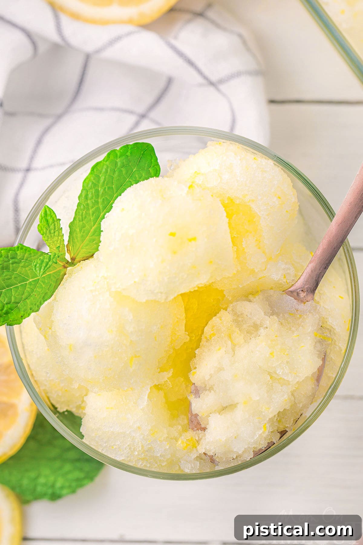 A top-down view of a glass of lemon sorbet, with a spoon gently scooping out a portion, highlighting its smooth texture.