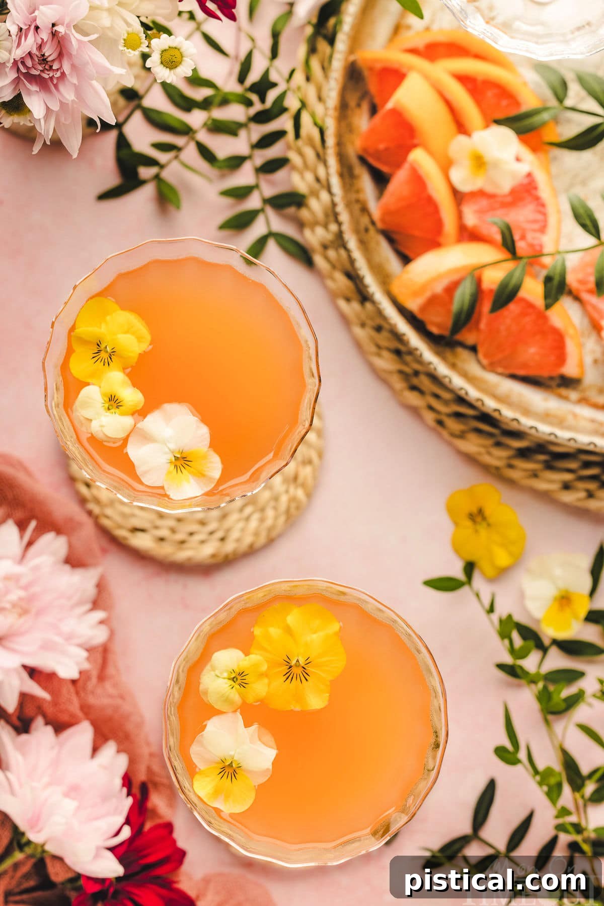 A Top down shot of french blonde cocktails on a pink surface with garnishes.