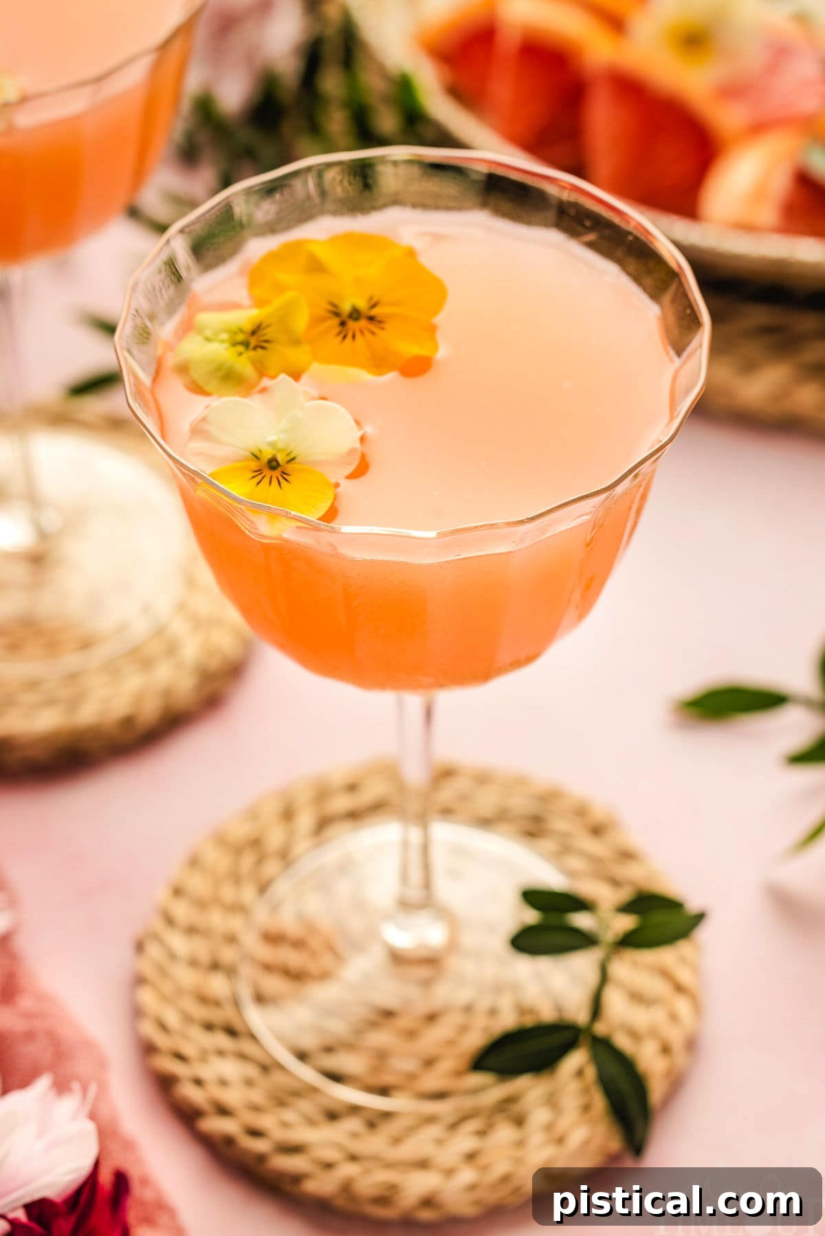 French Blonde Cocktail in a glass with edible flowers as a garnish.