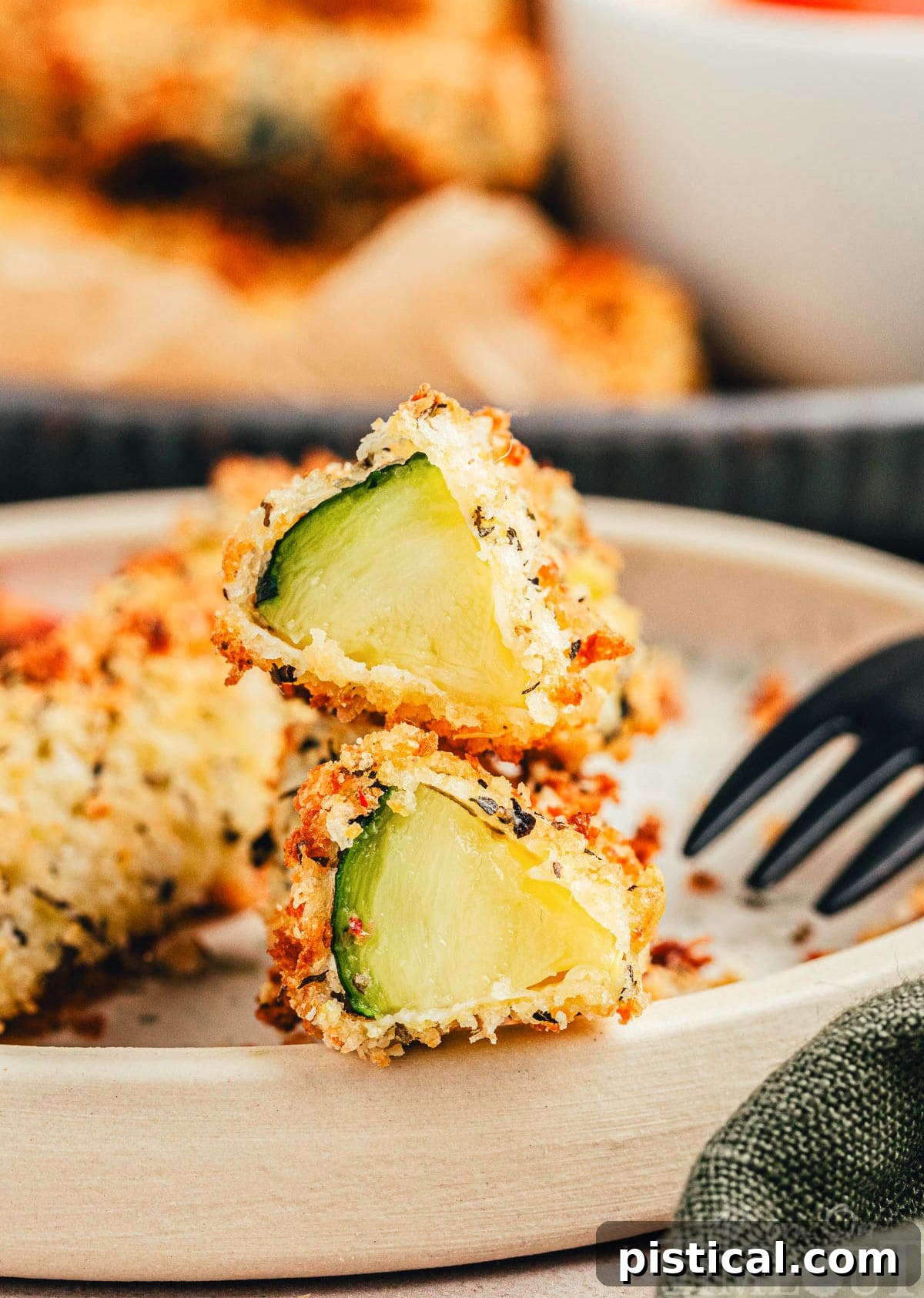 Air fryer zucchini fries cut in half on small plate, revealing the tender interior and golden-brown exterior, perfect for sharing.