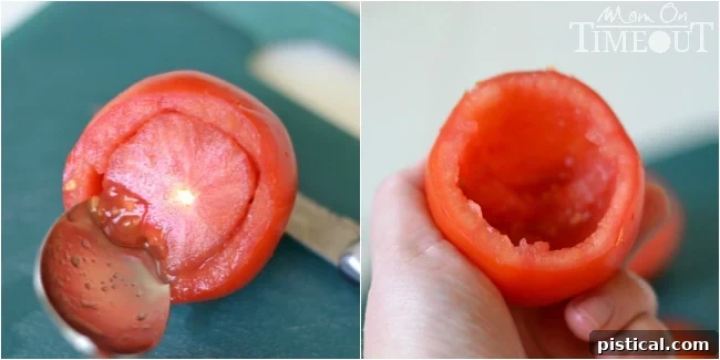Step-by-step image of a hand carefully scooping out the seeds and core from a fresh tomato, preparing it for stuffing.