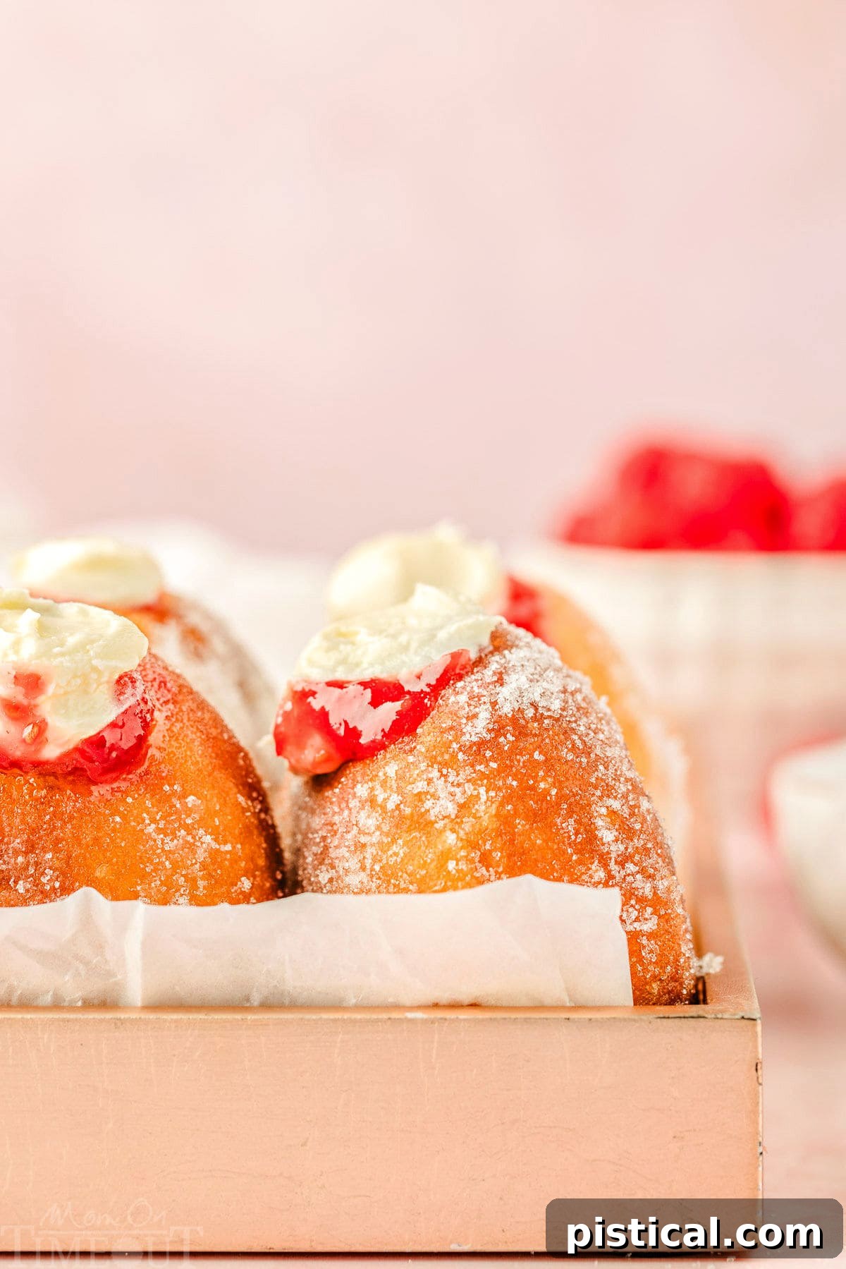 Straight-on shot of raspberry cheesecake donuts beautifully arranged in a pink box, ready for serving.