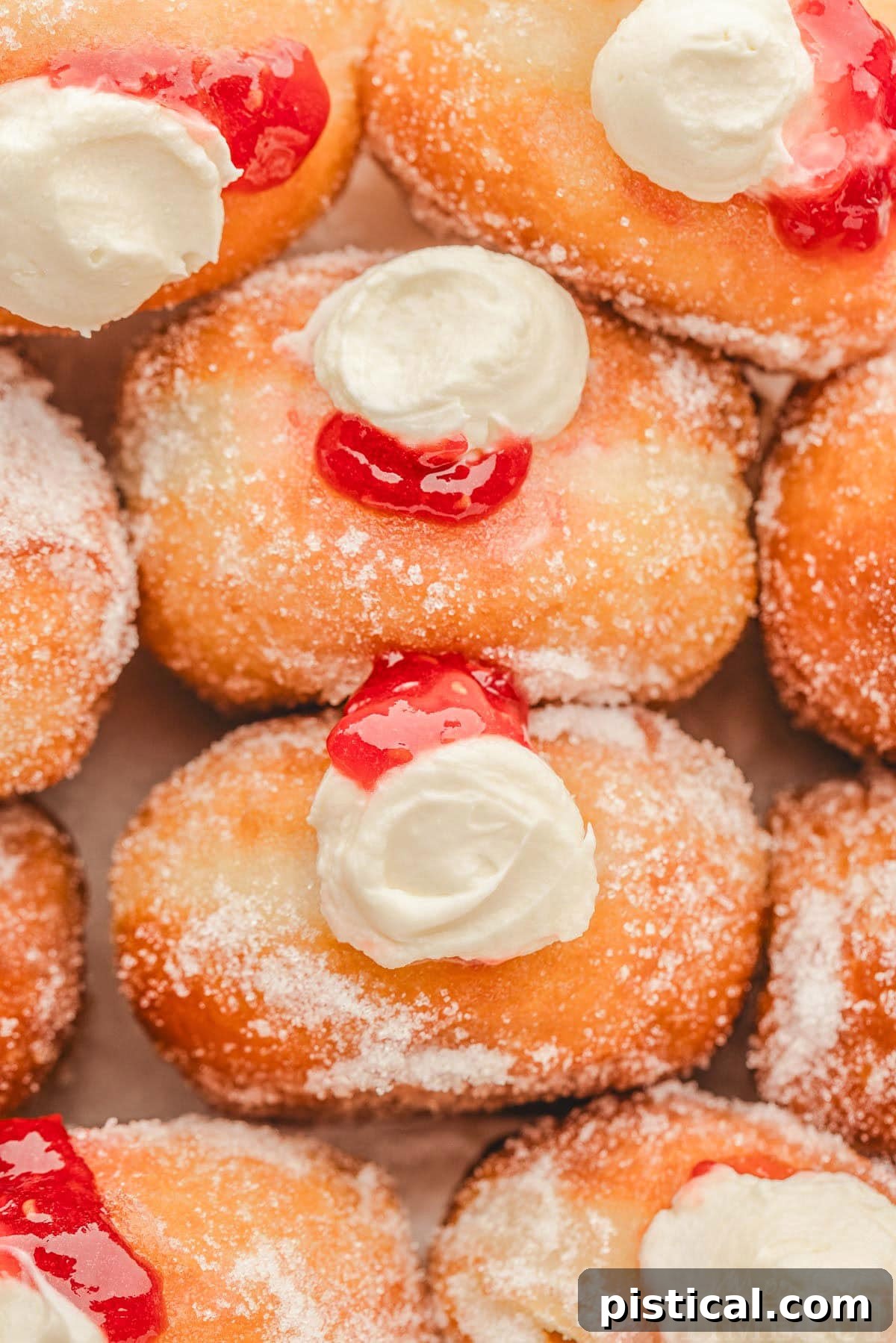 Top-down shot of a box filled with raspberry cheesecake stuffed donuts, rolled in sugar, ready to be enjoyed.