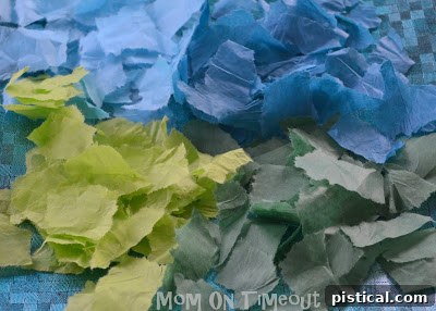 Child's hands tearing green and blue tissue paper for Earth Day craft