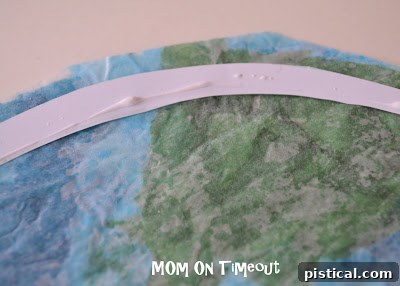 Gluing the circular paper frame onto the stained glass Earth