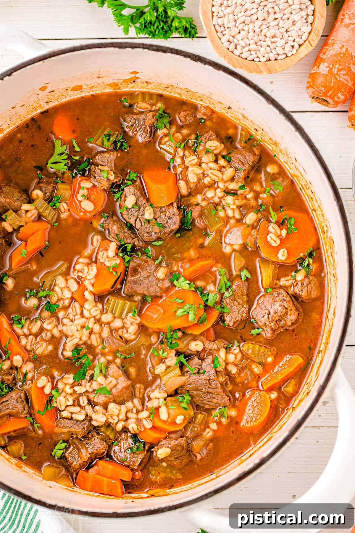 Hearty Beef Barley Stew 3 A top down shot of beef and barley soup in a white dutch oven.