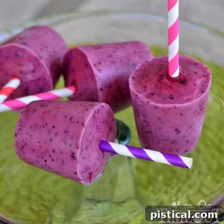 Stacked Greek Yogurt Berry Smoothie Pops on a wooden surface, ready to be enjoyed as a cool and healthy dessert.