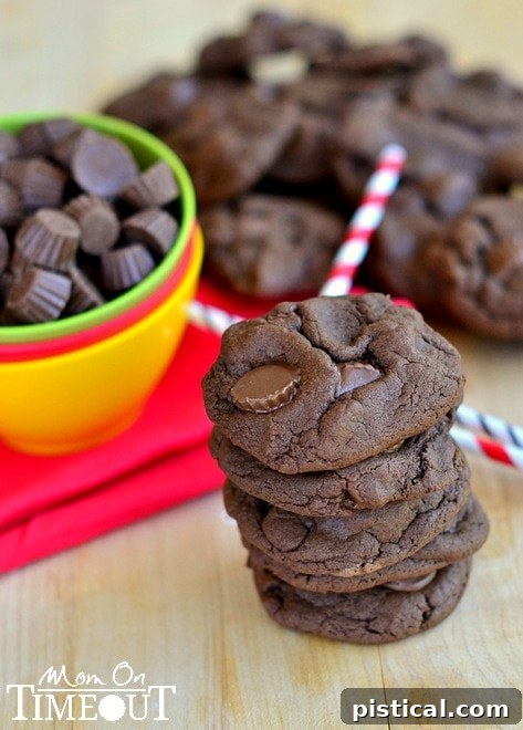 A stack of golden brown Chocolate Peanut Butter Cup Cookies with Reese's Minis, inviting you to grab one.
