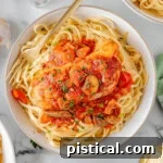 Slow Cooker Chicken Cacciatore on a bed of pasta on a white plate.