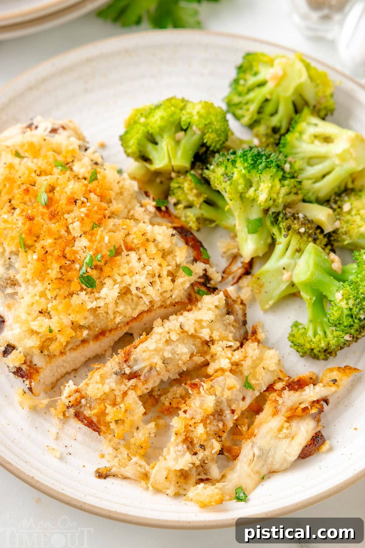 Steakhouse-Style Parmesan Crusted Chicken 2 Longhorn Parmesan crusted chicken on a white plate next to a side of broccoli.