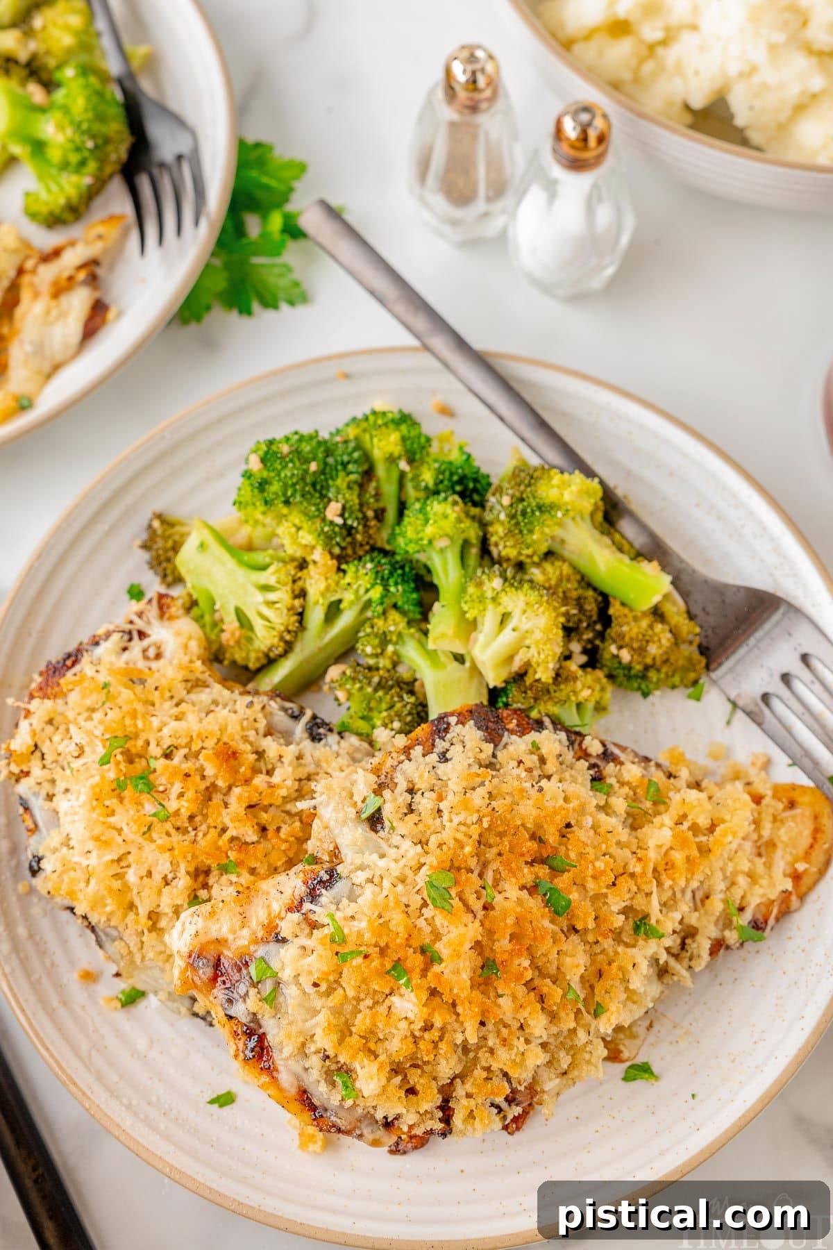 Steakhouse-Style Parmesan Crusted Chicken 6 Longhorn Parmesan crusted chicken on a white plate next to a side of broccoli.