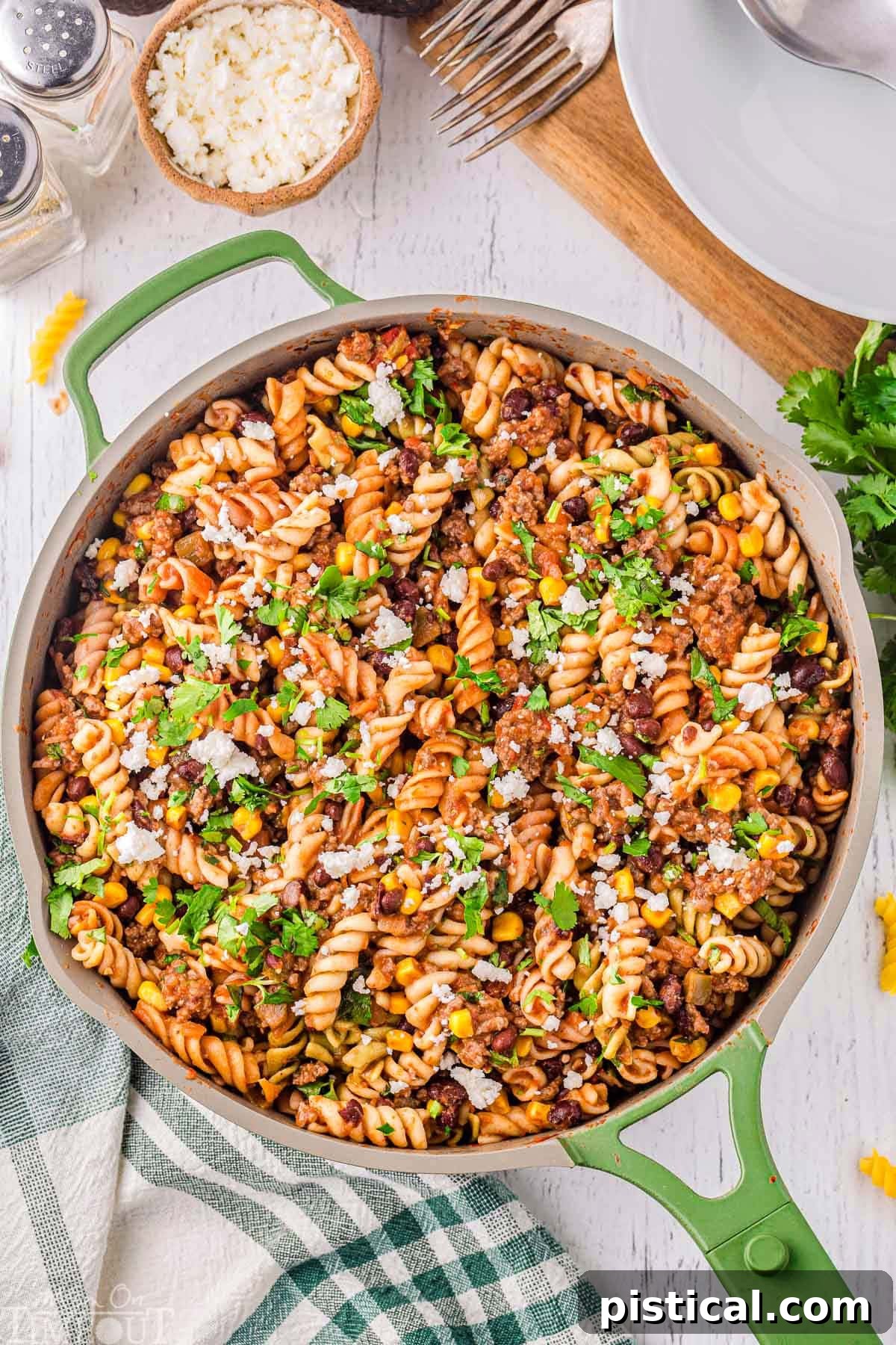 Tex-Mex Pasta Skillet 3 Top-down view of a vibrant green skillet filled with cooked taco pasta, garnished beautifully with fresh cilantro and crumbled queso fresco, ready to be served. The texture of the pasta and the rich sauce are clearly visible.