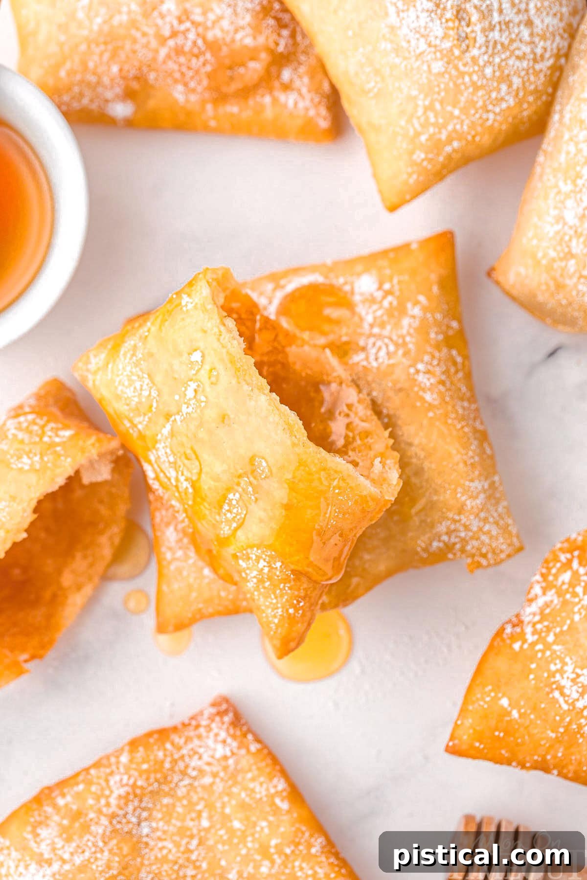 A sopapilla torn in half with additional sopapillas around it on a white surface.