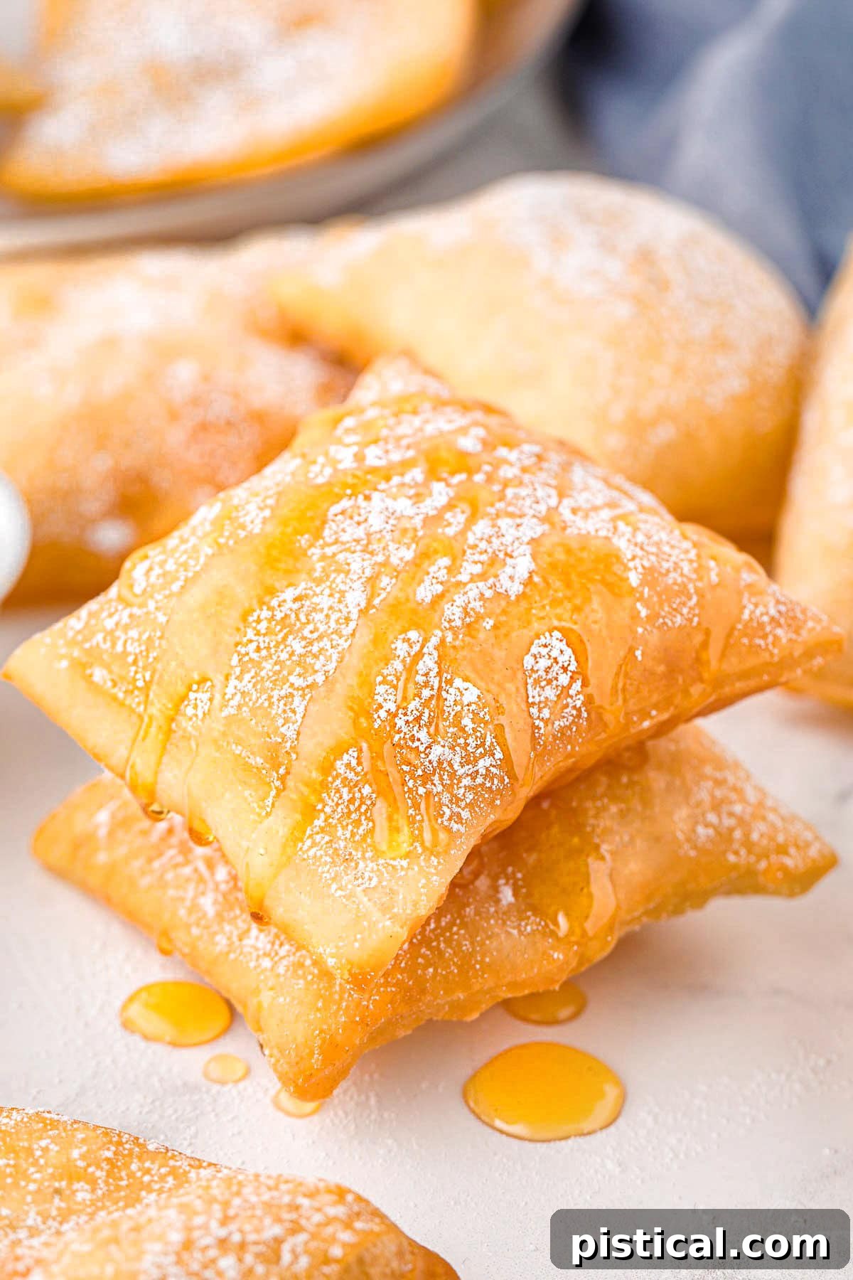 Two sopapillas stacked drizzled honey and topped with powdered sugar.