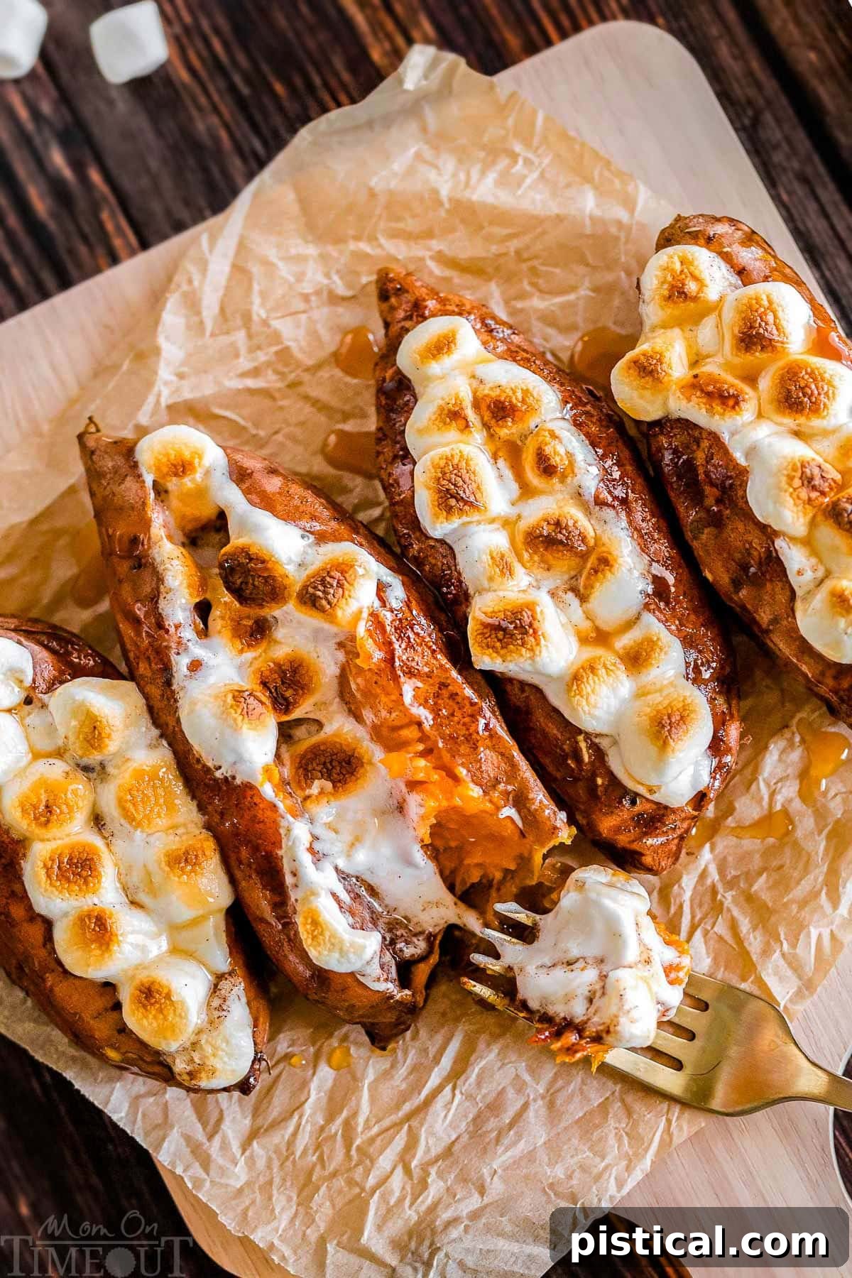 Twice baked sweet potatoes on a piece of parchment paper with a gold fork digging into a potato.