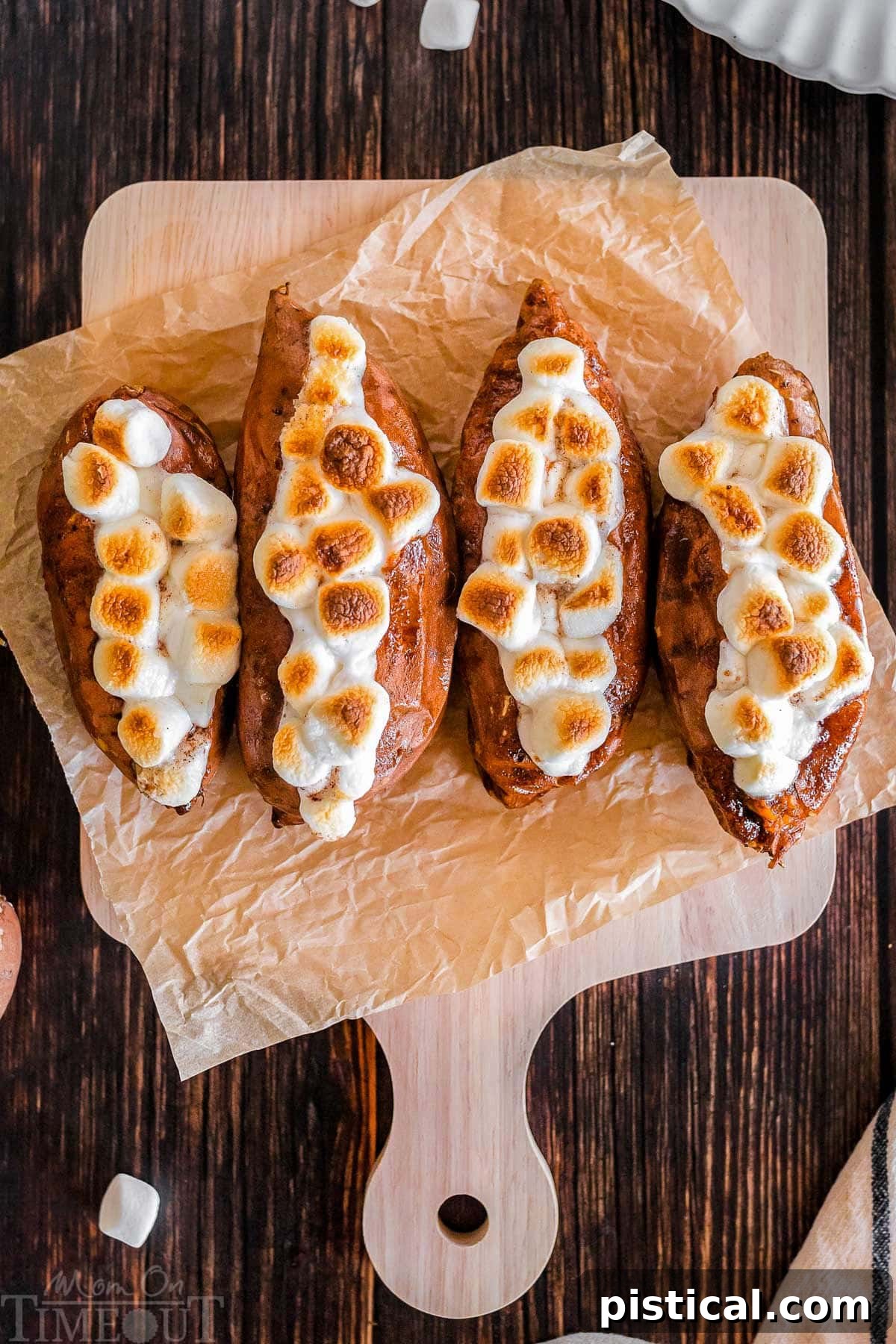 Twice baked sweet potatoes on a piece of parchment paper that's on a wood cutting board.