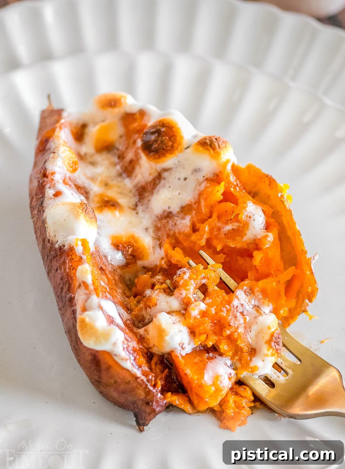 A twice baked sweet potato on a white plate with a gold fork in the potato.