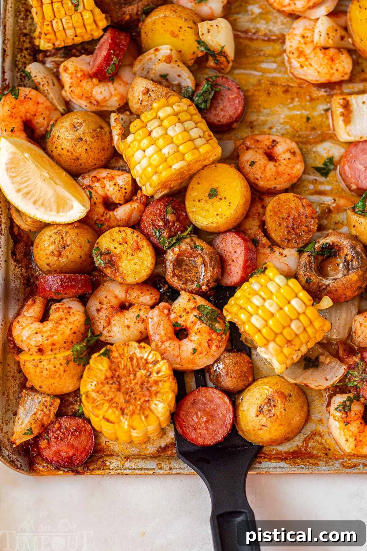 Sheet pan shrimp boil cooked and ready to be served right off the pan. Lemon wedges garnish the boil.