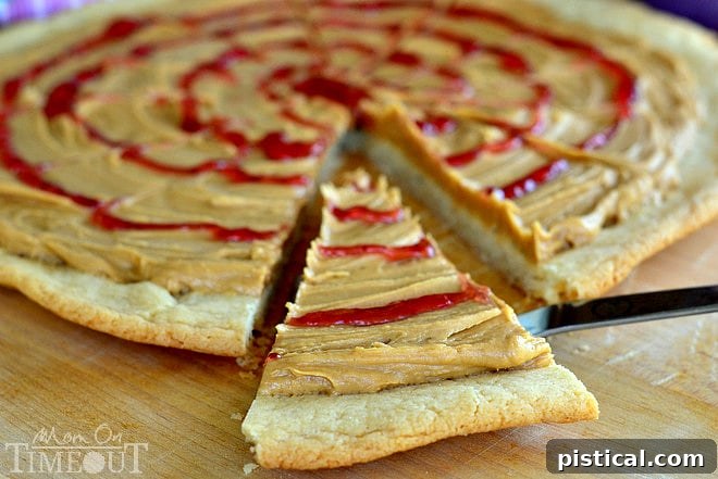 Peanut Butter and Jelly Sugar Cookie Pizza - Inspired by #Disney! from MomOnTimeout.com Our exquisite homemade Peanut Butter and Jelly Sugar Cookie Pizza, showcasing the smooth peanut butter frosting and vibrant jelly swirls on a perfectly baked sugar cookie base.