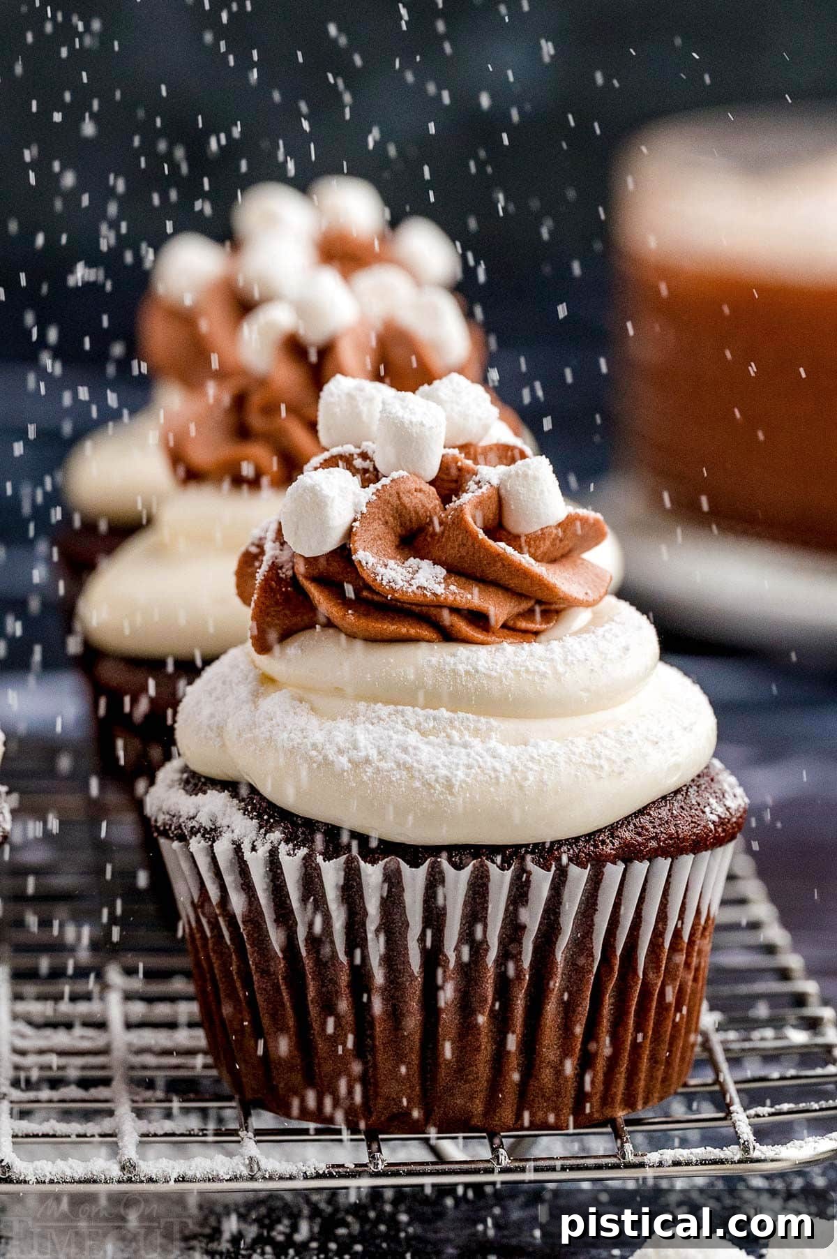 Velvet Hot Chocolate Cupcakes 4 Hot chocolate cupcakes cooling on a metal rack, lightly dusted with powdered sugar from above.
