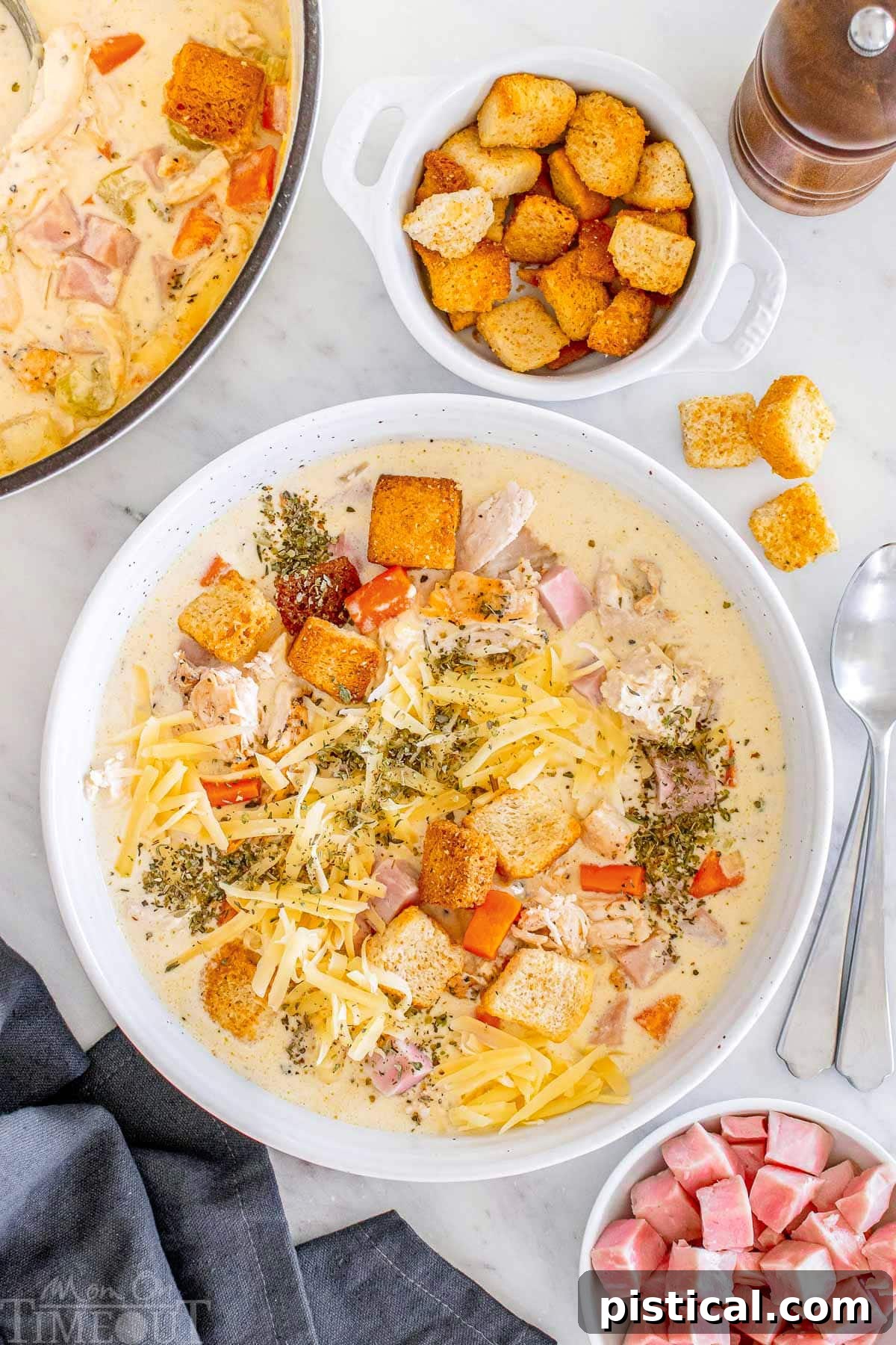 A Bowl of Cordon Bleu Comfort 2 A top down shot of chicken cordon bleu soup in a white bowl, garnished with fresh herbs and a sprinkle of cheese.