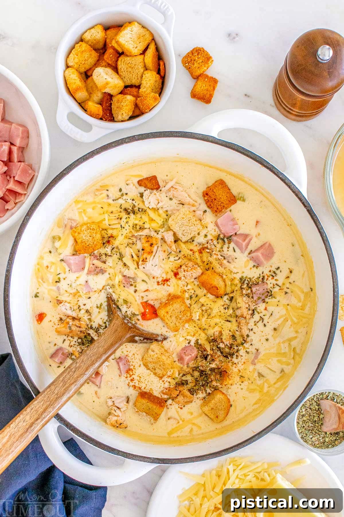 A Bowl of Cordon Bleu Comfort 8 Creamy chicken cordon bleu soup in a dutch oven with a wooden spoon, showcasing a generous portion ready to be served.