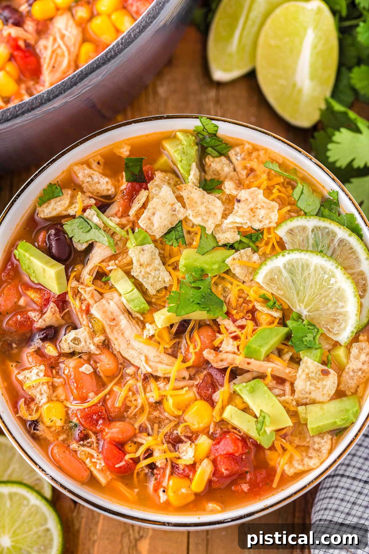 A top down shot of a bowl of chicken taco soup with fresh lime slices next to it, ready to be served.
