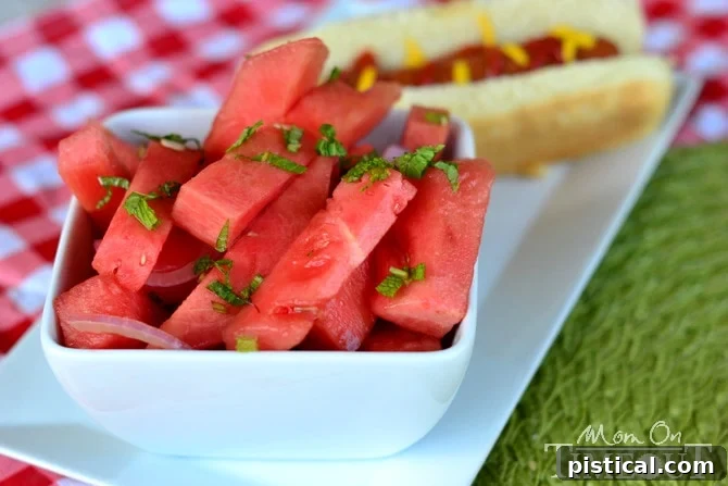 Close-up of Balsamic Watermelon Salad, showcasing the cubes of watermelon, mint leaves, and red onion, drizzled with dressing. MomOnTimeout.com