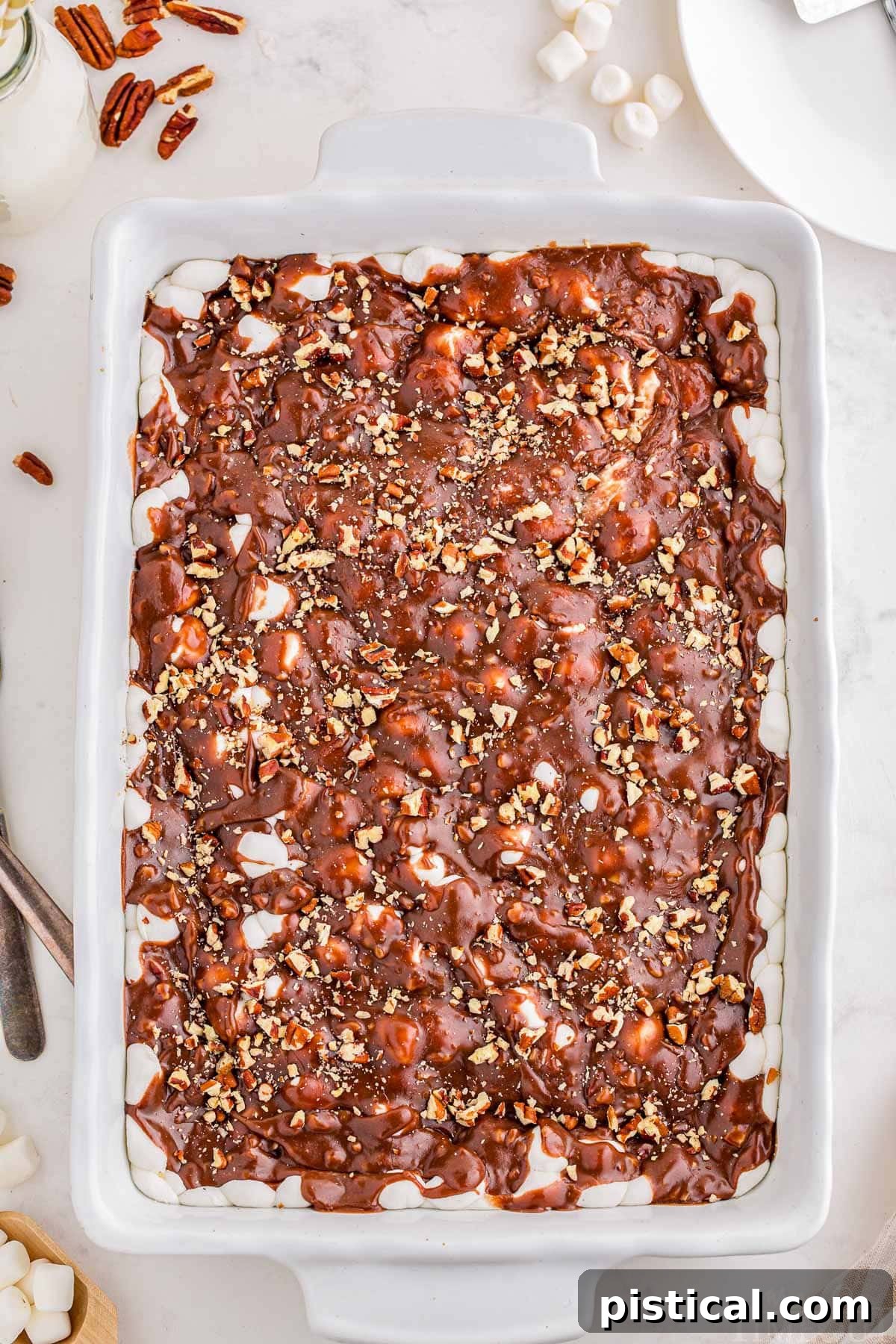 Decadent Delta Chocolate Dream 3 Top down view of a ready to be served Mississippi Mud Cake in a white baking dish. Pecans are scattered next to the dish.