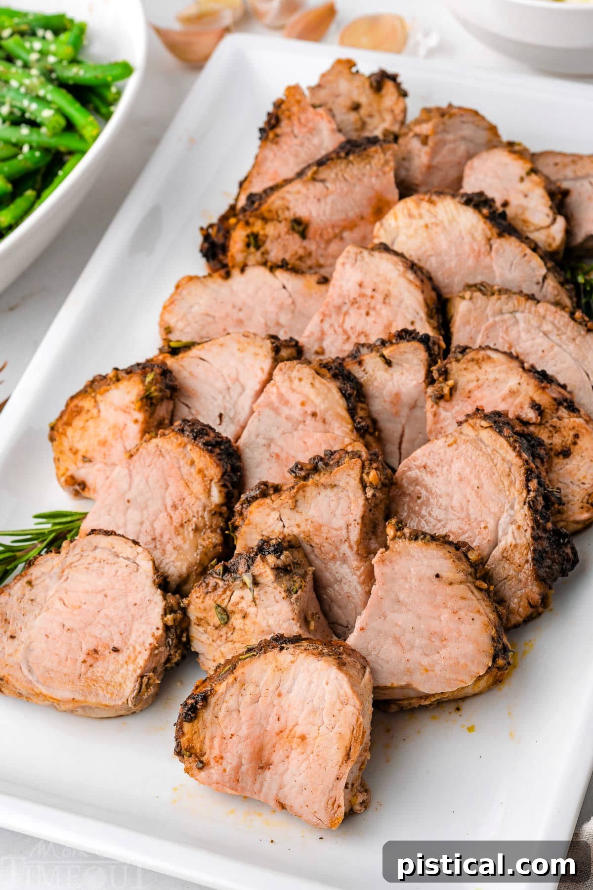 Air fryer pork tenderloin cut into medallions sitting on white rectangular platter.
