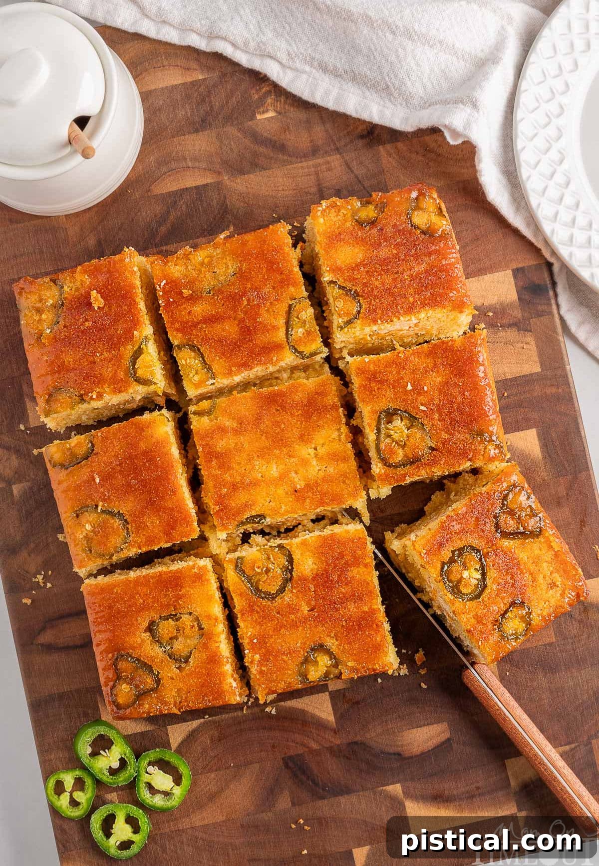 Top down view of jalapeno cornbread on a wood cutting board cut into 9 squares.