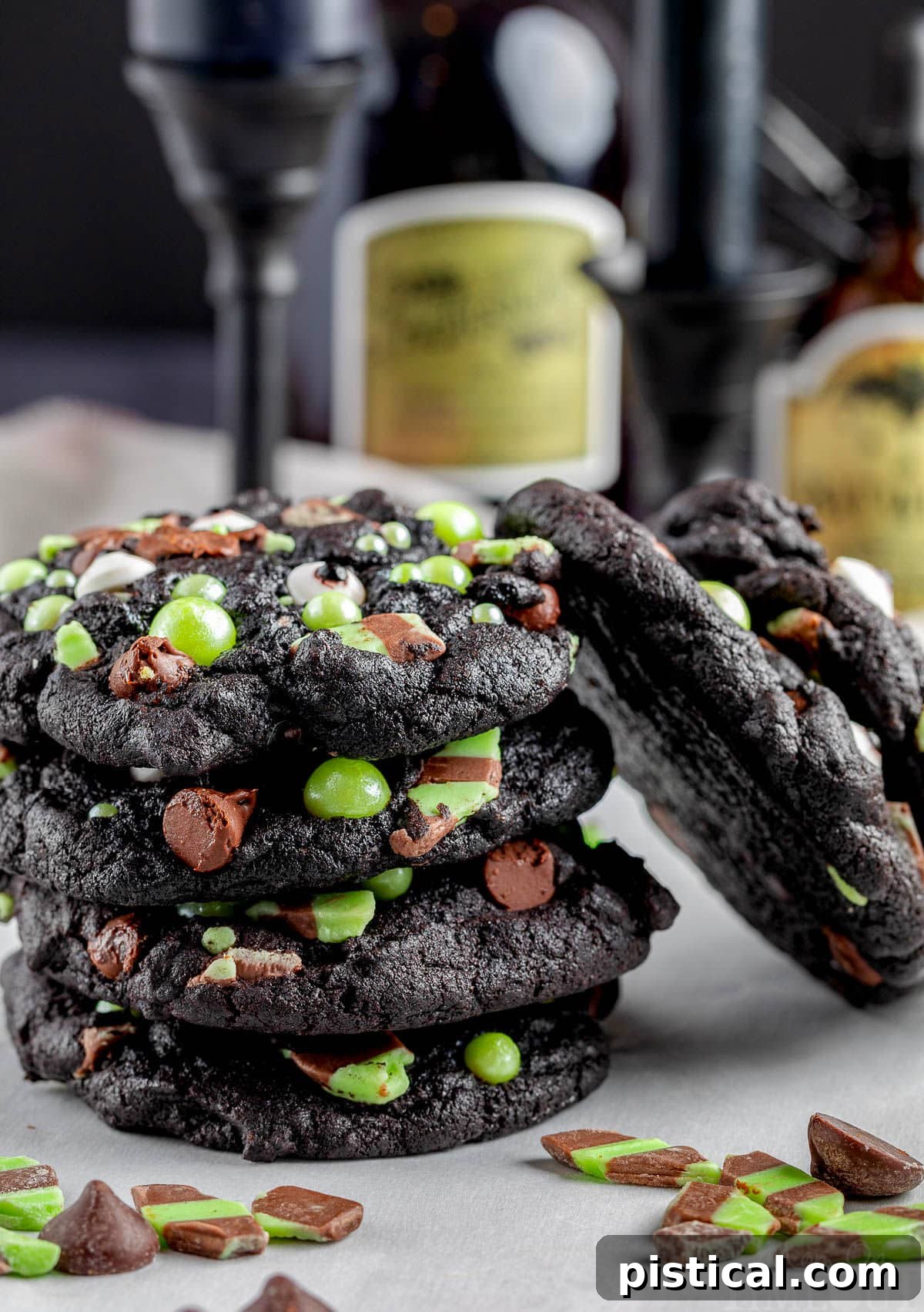 A delightful stack of monster Halloween cookies, generously filled with mint and chocolate chips, showcasing their dark color and festive decorations.