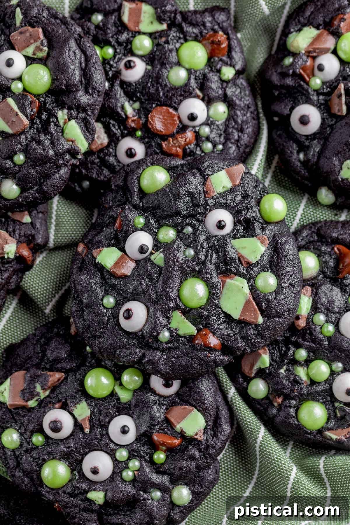 A delightful pile of Halloween monster cookies, artfully arranged on a soft green cloth, showcasing their vibrant colors and playful designs.