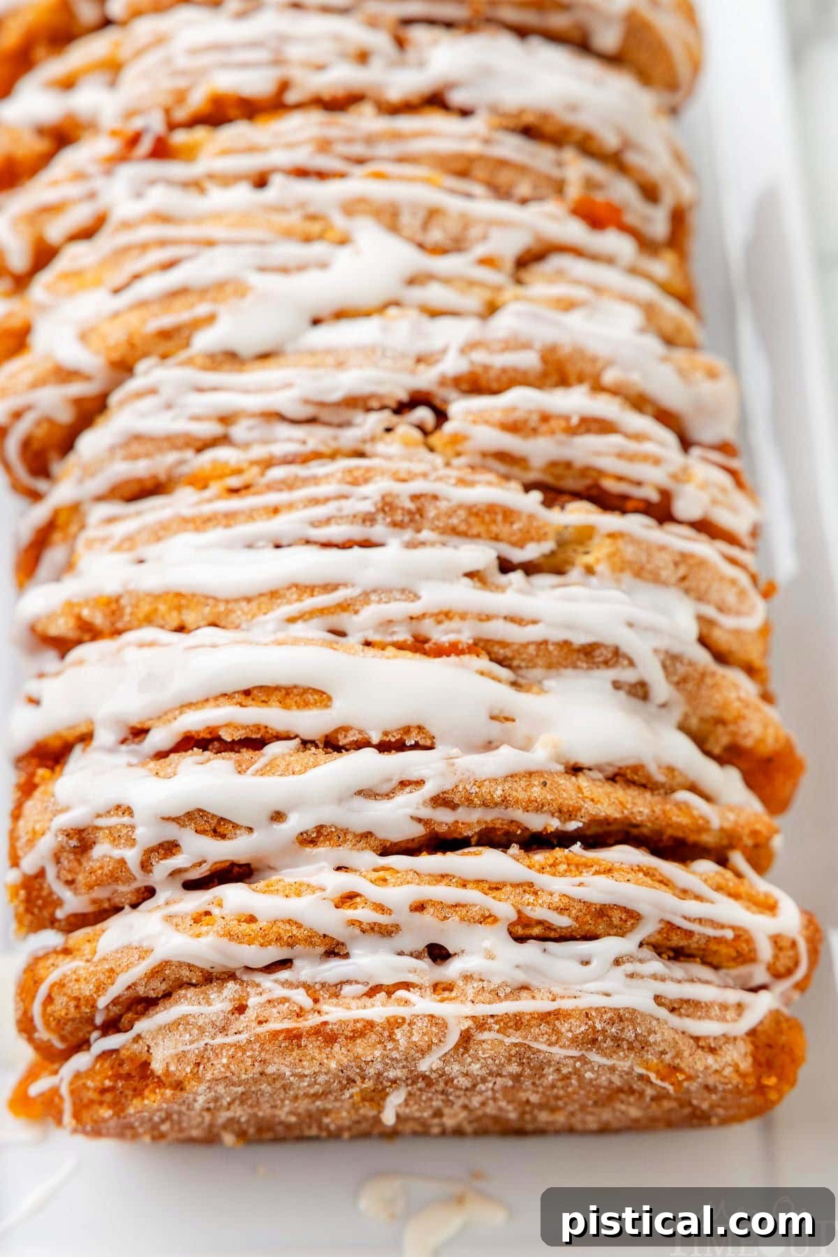 Close up look at the pull apart pumpkin loaf with a vanilla glaze on a white plate.