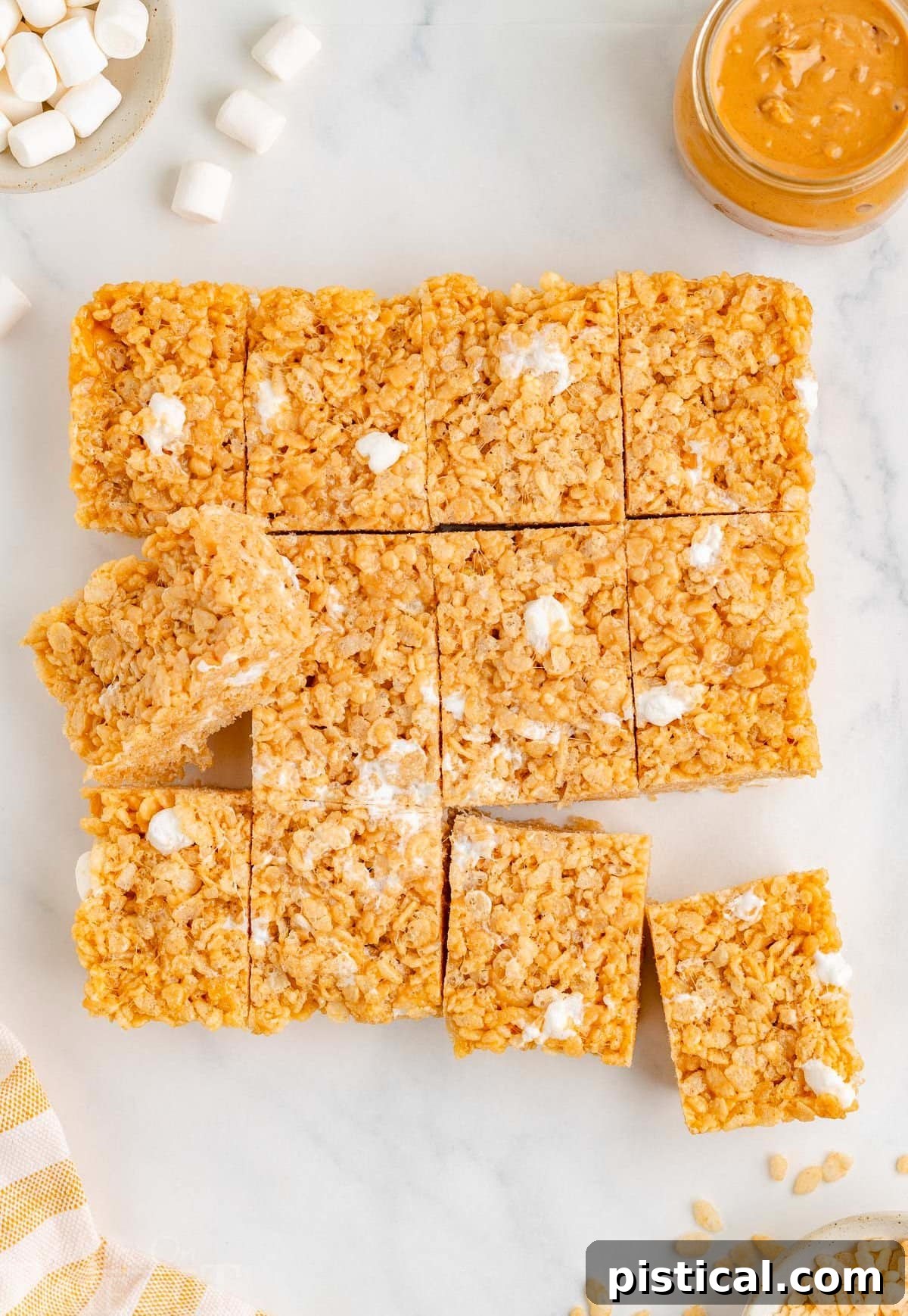 Top down view of rice krispie treats cut into squares on white surface, showing their even consistency.