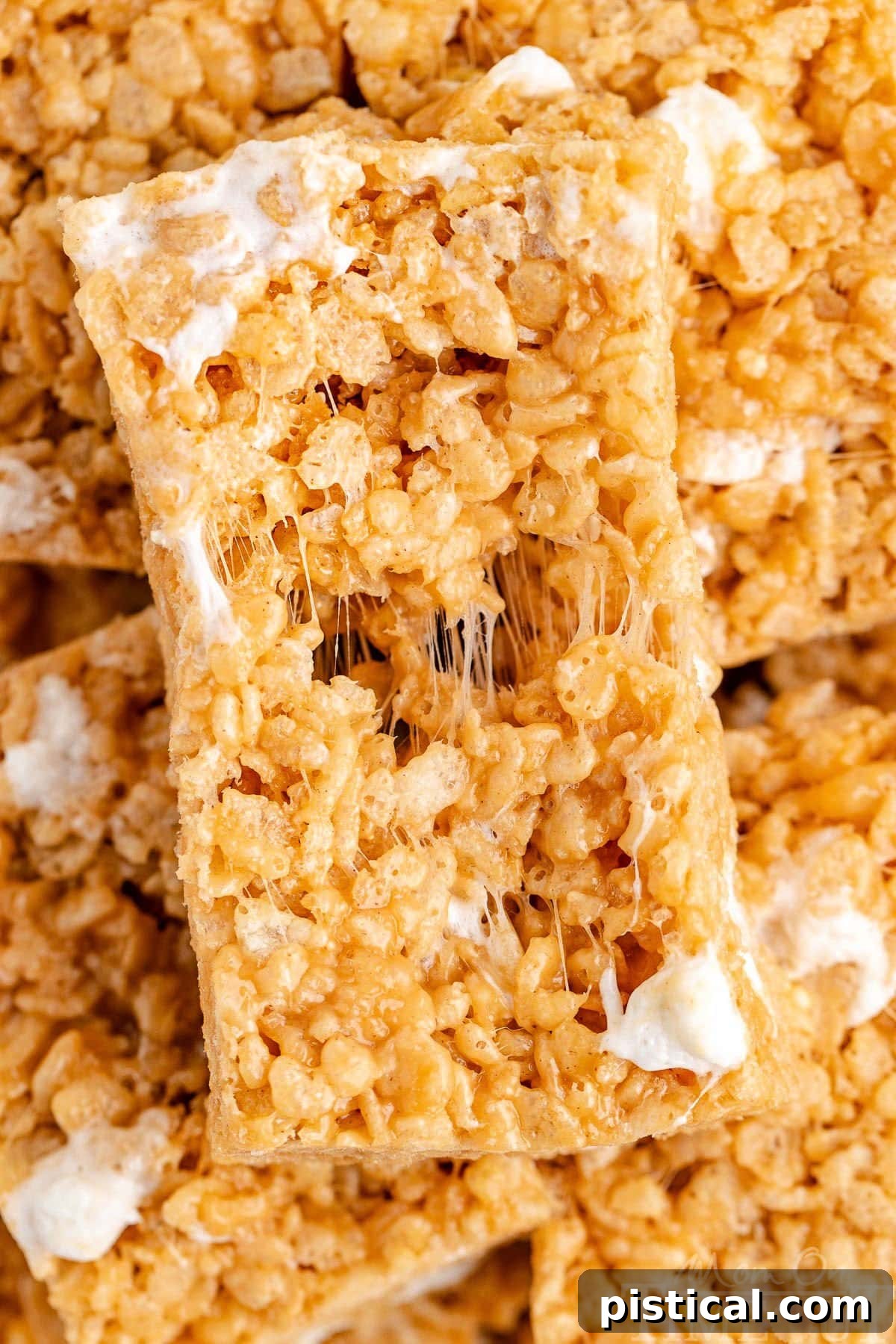 Peanut butter rice krispie treat pulled apart to show gooey marshmallows and chewy texture.