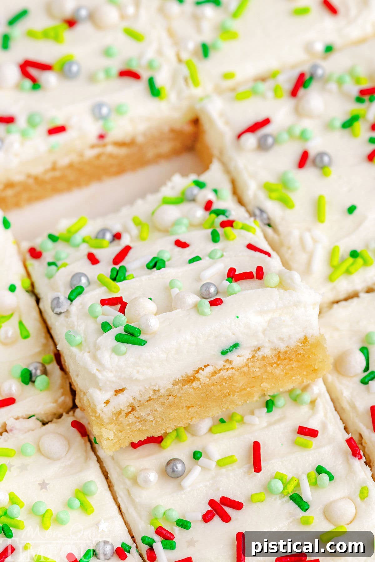 A perfectly square Christmas Sugar Cookie Bar, freshly cut and showing off its soft, thick base and generous layer of creamy white frosting, with festive sprinkles on top.