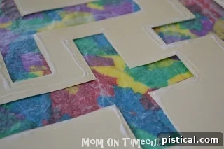 A thin line of glue applied around the perimeter of a paper cross template.
