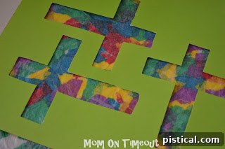 A paper cross template being glued onto the dried tissue paper and wax paper sheet.