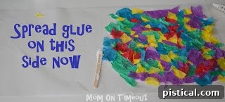 A hand spreading glue on the second half of the wax paper before folding it over the tissue paper mosaic.